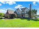 Beautiful traditional-style home with lush front lawn, mature trees, and lake views on a sunny day at 4843 Snowberry Bay Ct, Carmel, IN 46033