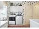 Charming laundry room with patterned wallpaper, white cabinetry, front load washer and dryer, and natural light at 4843 Snowberry Bay Ct, Carmel, IN 46033