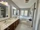 Bright main bathroom featuring double sinks, a soaking tub with jets, and a large window at 6036 Chinkapin Dr, Columbus, IN 47201