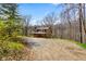 Charming stone home featuring dormer windows and a covered porch, nestled among trees on a gravel driveway at 6150 Red Day Rd, Martinsville, IN 46151