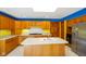 Eat-in kitchen boasts wood cabinets, tile backsplash, island with sink, and stainless steel refrigerator at 6780 E Woodland Ct, Mooresville, IN 46158