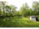 Sprawling backyard featuring lush green grass, mature trees, and a charming storage shed at 701 E Main St, Westfield, IN 46074