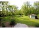 Expansive backyard featuring a small shed, landscaping, mature trees, and lush greenery at 701 E Main St, Westfield, IN 46074