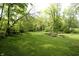 Expansive backyard featuring a large lawn and charming garden beds under the shade of mature trees at 701 E Main St, Westfield, IN 46074