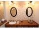 Bathroom featuring dual sinks, flower patterned wallpaper, and oval mirrors at 701 E Main St, Westfield, IN 46074