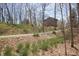 View of the home's wooded setting with gravel driveway and some early spring landscaping at 701 E Main St, Westfield, IN 46074