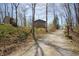 Exterior view of charming home with a long gravel driveway and wooded lot in spring at 701 E Main St, Westfield, IN 46074