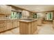 Spacious kitchen with light wood cabinetry, granite island cooktop, hardwood floors, and a breakfast nook with backyard views at 7249 Tuliptree Trl, Indianapolis, IN 46256