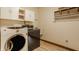 Bright laundry room featuring wooden floors, upper cabinets, and a convenient utility sink at 7249 Tuliptree Trl, Indianapolis, IN 46256