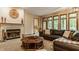 Bright living room featuring fireplace, large windows offering scenic views, and a leather sofa at 7249 Tuliptree Trl, Indianapolis, IN 46256