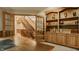 Open office with custom wood shelving, hardwood floors, a staircase view, and double french doors leading to the hallway at 7249 Tuliptree Trl, Indianapolis, IN 46256