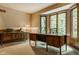 Inviting office space with a large desk, built-in shelves, wood trim, and bright windows overlooking the yard at 7249 Tuliptree Trl, Indianapolis, IN 46256