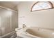 Modern bathroom featuring a tiled shower, corner bathtub, toilet, and arched window at 757 Howe Dr, Carmel, IN 46032
