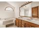 Bright bathroom with double sink vanity, large mirror, arched window, and tub at 757 Howe Dr, Carmel, IN 46032