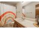 Bright bathroom with neutral countertop, rainbow shower curtain and contemporary fixtures at 757 Howe Dr, Carmel, IN 46032