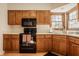 Functional kitchen features warm wood cabinetry, black appliances, and a bright window over the sink at 757 Howe Dr, Carmel, IN 46032