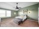 Calm bedroom featuring green walls, a ceiling fan, a comfortable bed, and natural light from the window at 8452 Ironhill Ct, Indianapolis, IN 46259