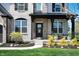 Charming covered front porch with decorative plants, black door, and a welcoming entryway, surrounded by greenery at 8452 Ironhill Ct, Indianapolis, IN 46259