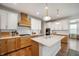 Bright kitchen with an island, hood vent, white upper cabinets, wood-look lower cabinets, and modern lighting at 8452 Ironhill Ct, Indianapolis, IN 46259