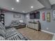 Finished basement boasts gray walls, wood floor, TV, and comfortable gray leather furniture with cupholders at 8926 New Heritage Ct, Indianapolis, IN 46239
