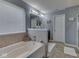 Soaking tub beneath a window adds natural light to this primary bathroom featuring an adjacent toilet room at 8926 New Heritage Ct, Indianapolis, IN 46239