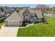 Aerial view of a brick home featuring a manicured lawn extending to a serene lake at 1016 Silver Lake Ct, Greenwood, IN 46142