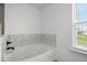 Bright bathroom featuring a soaking tub with decorative tile backsplash and a window with natural light at 10524 Broadford St, Indianapolis, IN 46239