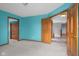 Bright bedroom with teal walls, neutral carpet, and wood trim leading to a hallway and closet at 1121 Retford Ct, Greenwood, IN 46143