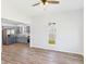 Bright living room featuring light walls, wood floors, and a ceiling fan; kitchen visible in background at 1217 W 6Th St, Anderson, IN 46016