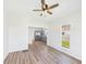 Bright living room featuring light walls, wood floors, and a ceiling fan; kitchen visible in background at 1217 W 6Th St, Anderson, IN 46016