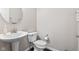 This powder room features a pedestal sink, round mirror, and a toilet with gray walls at 1334 Winfield Way, Greenwood, IN 46143