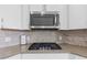 Close up of range with stainless microwave, granite countertops and mosaic backsplash at 1334 Winfield Way, Greenwood, IN 46143