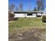 A single-story home featuring light grey siding, large front window, and a well-maintained lawn in a residential neighborhood at 1618 E 24Th St, Muncie, IN 47302