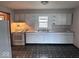 Functional kitchen with white cabinets, laminate countertops, standard appliances, and a window over the sink area at 1618 E 24Th St, Muncie, IN 47302
