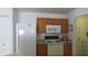 Practical kitchen with white appliances, wooden cabinets, and a view to a laundry area at 1833 Southernwood Ln, Indianapolis, IN 46231