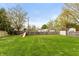 Wide open backyard with mature trees and a wooden playset, enclosed by a wood fence at 204 S Hougland St, Trafalgar, IN 46181