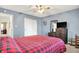 Cozy bedroom features a red and black plaid bedspread, ceiling fan, and blue accent wall at 209 Allen Ln, New Whiteland, IN 46184