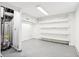 Unfinished basement with water heater, utility shelving, white walls, and concrete flooring; ideal for storage or customization at 2114 N Dexter St, Indianapolis, IN 46202