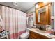 Charming bathroom featuring a vanity with an oak cabinet, a mirror and a shower with a striped curtain at 3335 W 400 N, Anderson, IN 46011