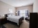 Cozy bedroom with neutral walls, carpet flooring, and large window with blue patterned curtains at 4631 Belair Cir, Plainfield, IN 46168