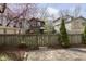 Backyard and fence with a wooden gate, tulips and a young evergreen at 5110 Riverview Dr, Indianapolis, IN 46208