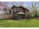 View of the home with wood fence, mature trees and lush green grass at 5110 Riverview Dr, Indianapolis, IN 46208