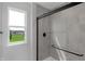Bathroom featuring a sleek, glass-enclosed shower with gray tile and exterior window at 5218 Triple Crown Way, Indianapolis, IN 46237