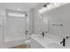 Bathroom featuring a double vanity, tub with shower, wood grain tile, and modern lighting at 5218 Triple Crown Way, Indianapolis, IN 46237