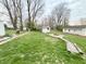 Spacious backyard with lush lawn, mature trees, fire pit, and path at 5845 South St, Stilesville, IN 46180