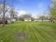Expansive backyard featuring a level lawn, mature trees, and a fire pit area, perfect for outdoor gatherings at 6107 Rural Dr, Indianapolis, IN 46227