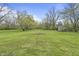 Spacious backyard featuring a large grassy area, mature trees, and a circular stone fire pit at 6107 Rural Dr, Indianapolis, IN 46227