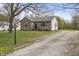 Stone facade home with a long gravel driveway, mature trees, and a well-maintained lawn at 6107 Rural Dr, Indianapolis, IN 46227
