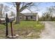 View of stone facade home, gravel driveway, and mailbox with house number, framed by a large tree at 6107 Rural Dr, Indianapolis, IN 46227