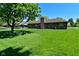 Exterior view of a brick home, showing a large lawn, mature trees, and patio area at 6318 Dahlia Dr, Indianapolis, IN 46217